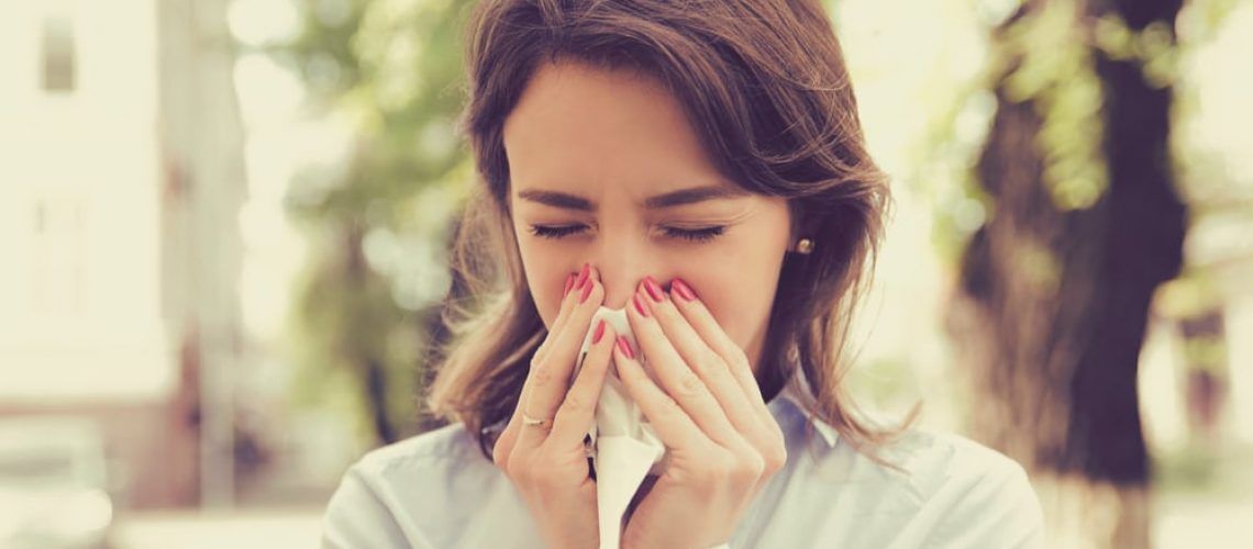 Woman blowing her nose due to allergies